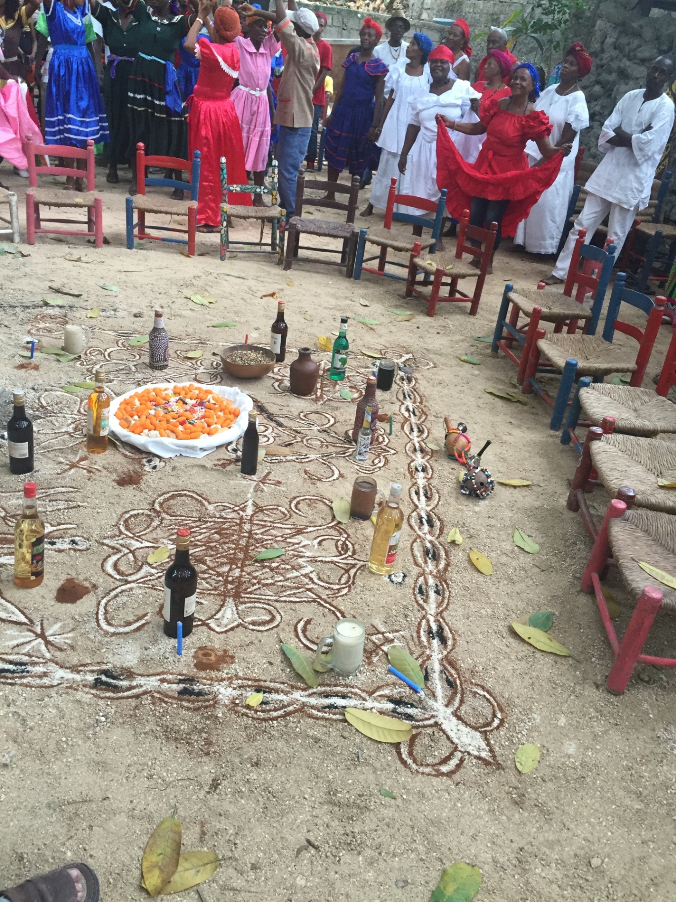 Community members in colorful dress gathered around a ceremonial ground in Haiti